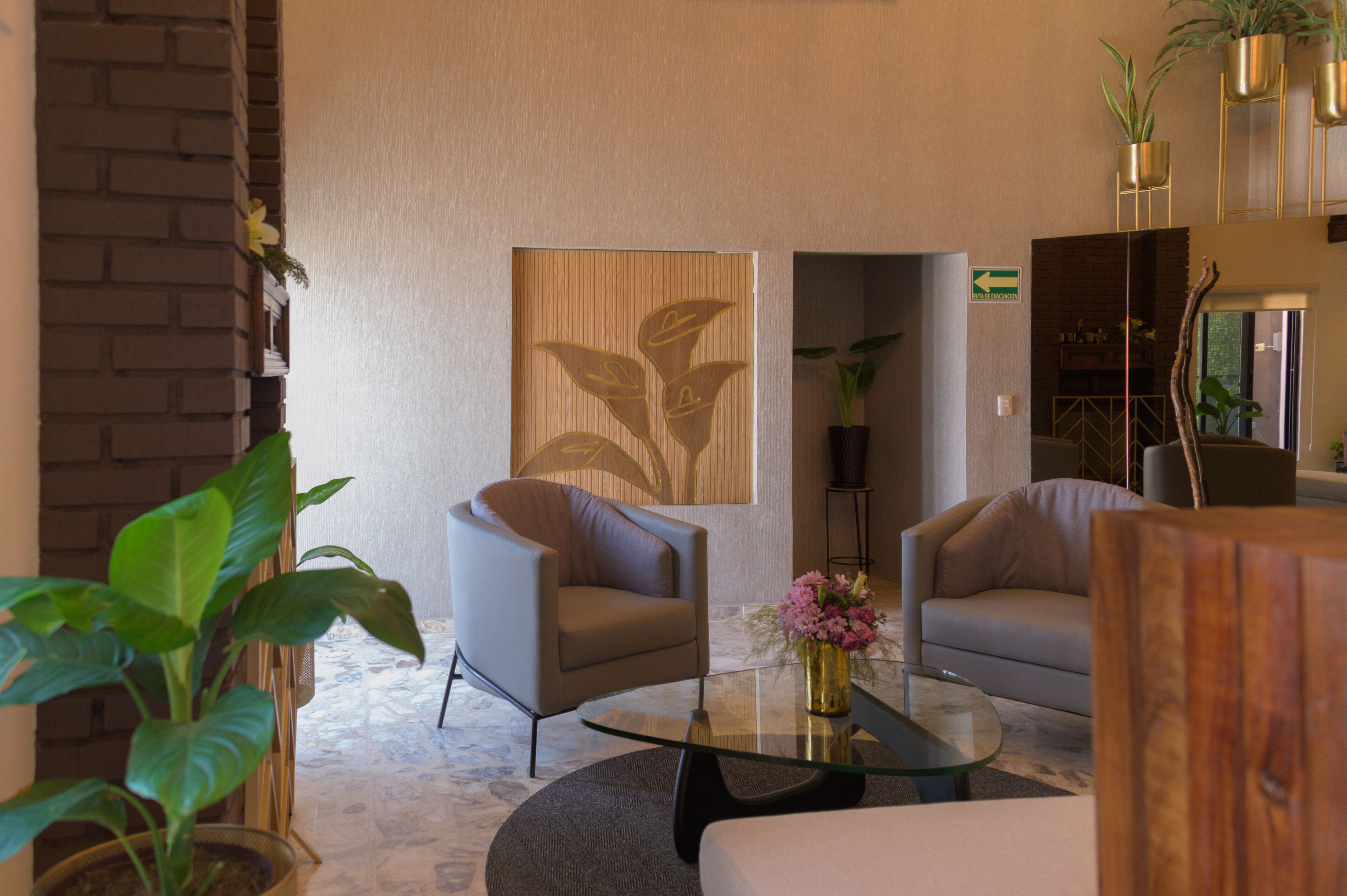 Un hall d’entrée moderne avec deux canapés, une table basse en verre et des plantes en pot.