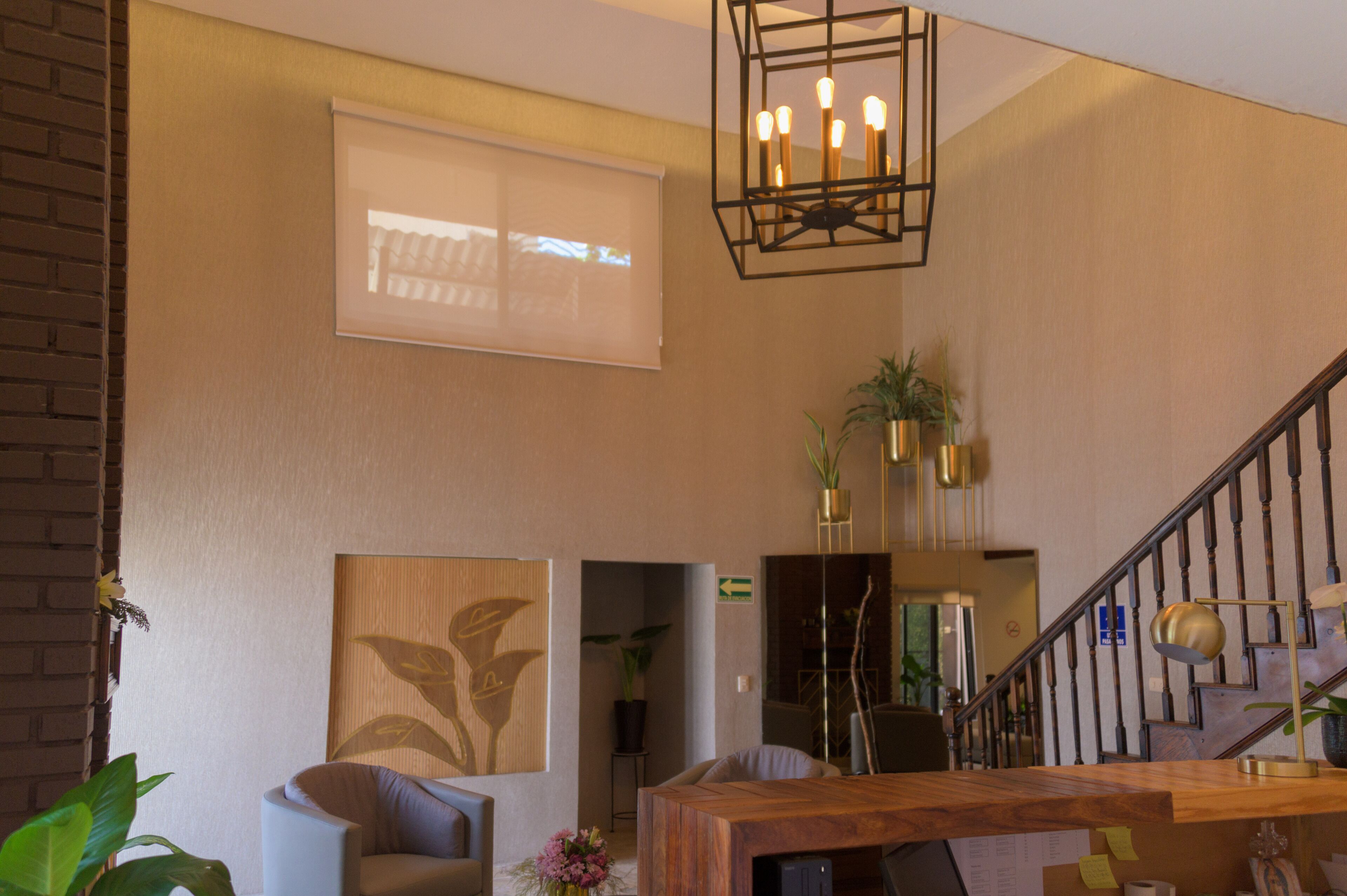 A modern interior with a wooden reception desk, a staircase, and a large window with a view.