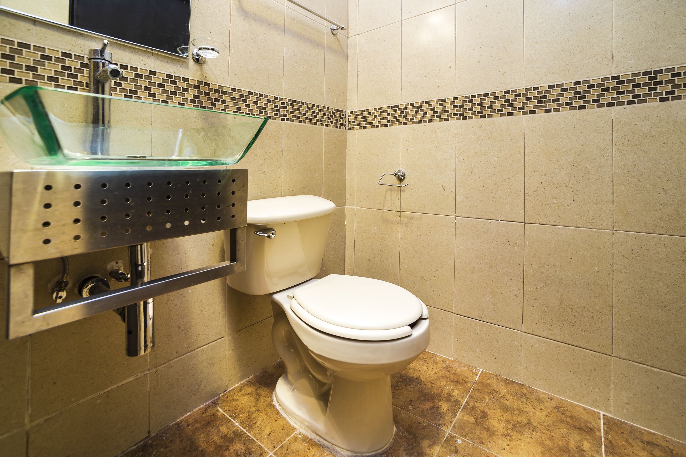 Une salle de bain comprenant des toilettes, un lavabo en verre et une douche carrelée.