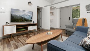 Ein modernes Wohnzimmer mit Flachbildfernseher, einer Holzunterhaltungseinheit und einem blauen Sofa.