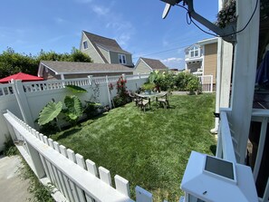 A backyard with a white fence, a lawn, a table with chairs, and a potted plant. - Meticulously clean and very cozy just blocks to the beach!  (Ventnor City)