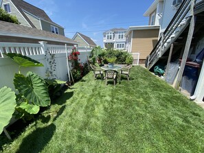 A well-maintained backyard with a lawn, a small table with chairs, and a white picket fence. - Meticulously clean and very cozy just blocks to the beach!  (Ventnor City)