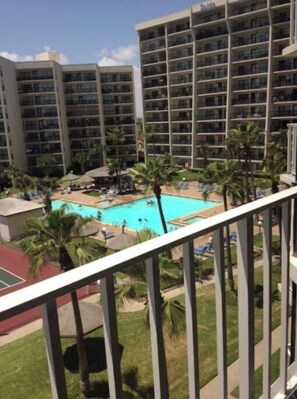 Enjoy a resort-like atmosphere with a pool surrounded by lush greenery and lounge chairs.