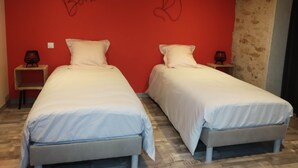 Dos camas individuales con ropa de cama blanca en una habitación con paredes rojas.