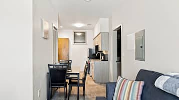A compact living space with a dining area, kitchenette, and a sofa with a colorful pillow.