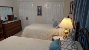 A bedroom with two beds, a dresser, a lamp, and a framed picture on the wall.
