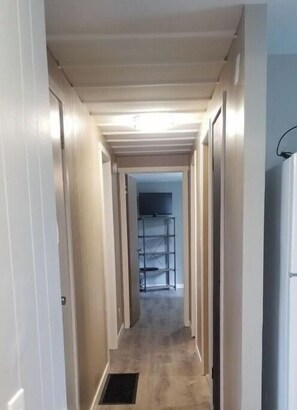 Stylish hallway with doors leading to various rooms, featuring a wooden floor and recessed lighting.