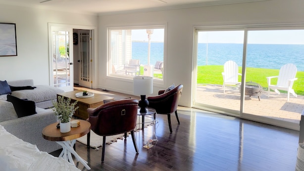 A spacious living area with a view of the ocean, a dining table, and comfortable seating.