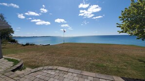A grassy yard with a flagpole and a view of a calm body of water.