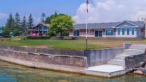 A waterfront property with a flagpole, a dock, and a building with large windows.