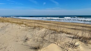 A beach with sand dunes and waves. - Steps to the Sand! Ocean views! Hot tub! Close to Pier! Dogs! KD0222 (Kill Devil Hills)