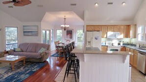 A spacious living area with a dining table and chairs, a kitchen with wooden cabinets, and a ceiling fan. - Corolla Light Resort! Dogs! Heated Pool! Hot tub! Walk to restaurants! C1131 (Corolla)
