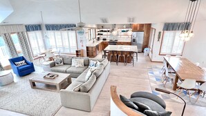 A spacious living area with a large sofa set, a dining table, and a kitchen in the background. - Ocean Front w/Pool! Hot Tub, Quiet Neighborhood, D0130 (Duck)