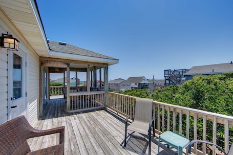 A wooden deck with a covered seating area, a chair, and a small table.