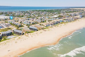Luchtbeeld van een kustgebied met woningen, een strand en een groot wateroppervlak.