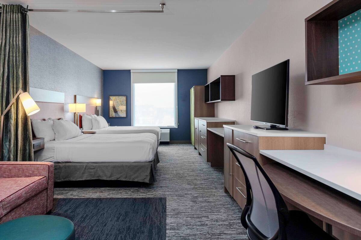 Een hotelkamer met een bed, bureau, televisie en raam.