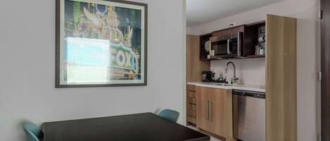 A compact kitchen with wooden cabinets, a microwave, and a dishwasher.