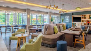 Uma área de lounge moderna com disposição de assentos, uma televisão e uma máquina de café.