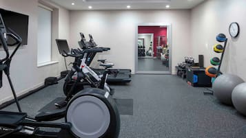 A gym with treadmills, stationary bikes, and exercise balls.
