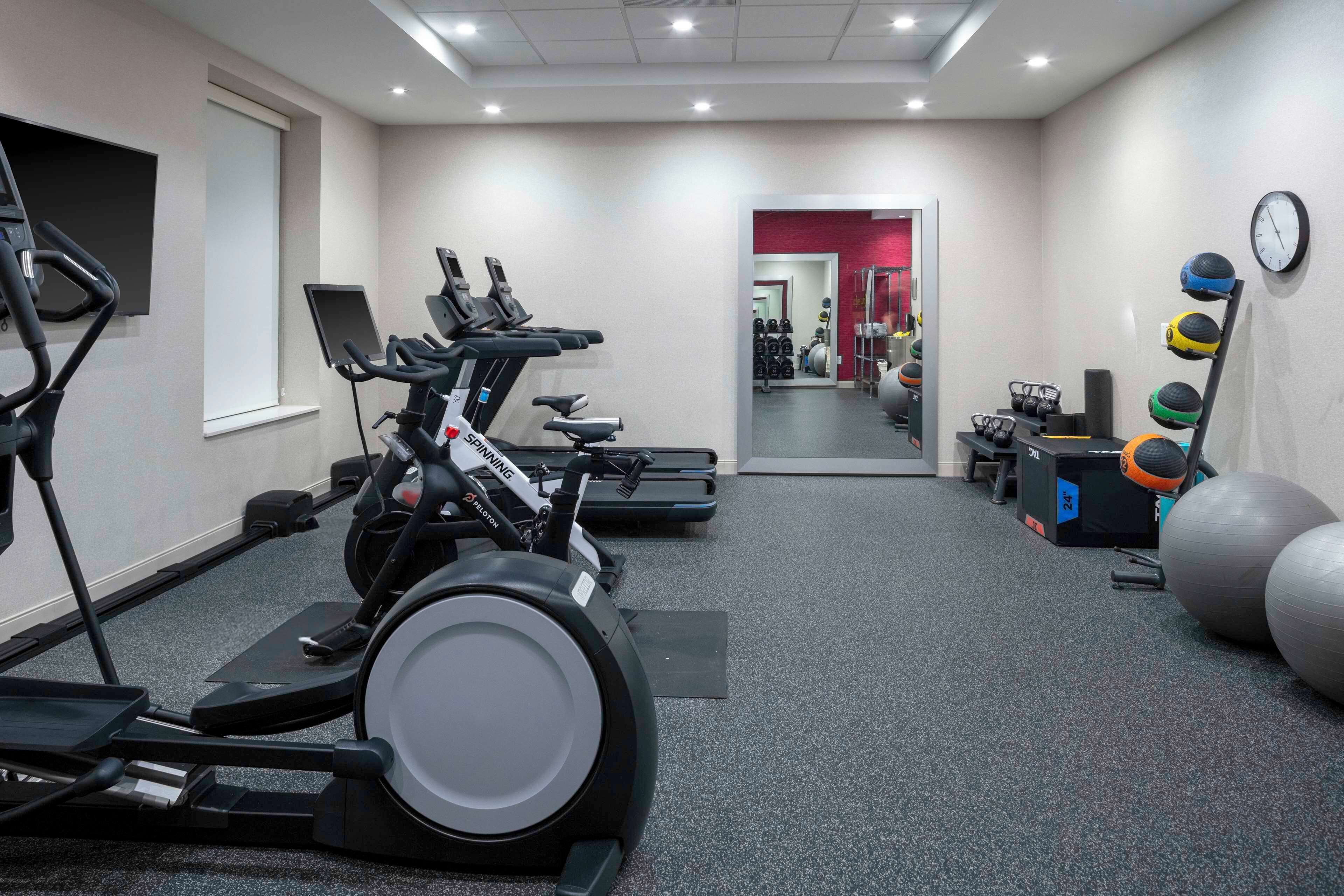 Une salle de sport équipée de tapis de course, de vélos d’appartement et de ballons d’exercice.