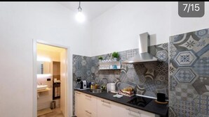 A modern kitchen with patterned tiles, a black countertop, and a stainless steel sink. - Studios Toledo 355. (Napoli)