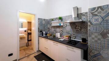 Una cocina moderna con baldosas estampadas, encimera negra y pileta de acero inoxidable.