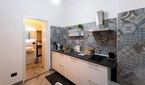 Een moderne keuken met behangtegels, een zwart aanrecht en een roestvrijstalen spoelbak.