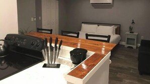 A compact kitchen with a stove, a knife block, and a dining area with chairs. - ✪King Bed Studio✪ in Suburbs -Perfect Long Term Stay (Clifton Heights)