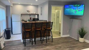 A modern kitchen with a dining area, a TV mounted on the wall, and a shower visible through an open door. - ✪King Bed Studio✪ in Suburbs -Perfect Long Term Stay (Clifton Heights)