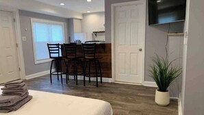A bedroom with a bed, a desk with chairs, a television, and a potted plant. - ✪King Bed Studio✪ in Suburbs -Perfect Long Term Stay (Clifton Heights)