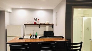 A modern kitchen with a wooden dining table, black chairs, and a built-in oven. - ✪King Bed Studio✪ in Suburbs -Perfect Long Term Stay (Clifton Heights)