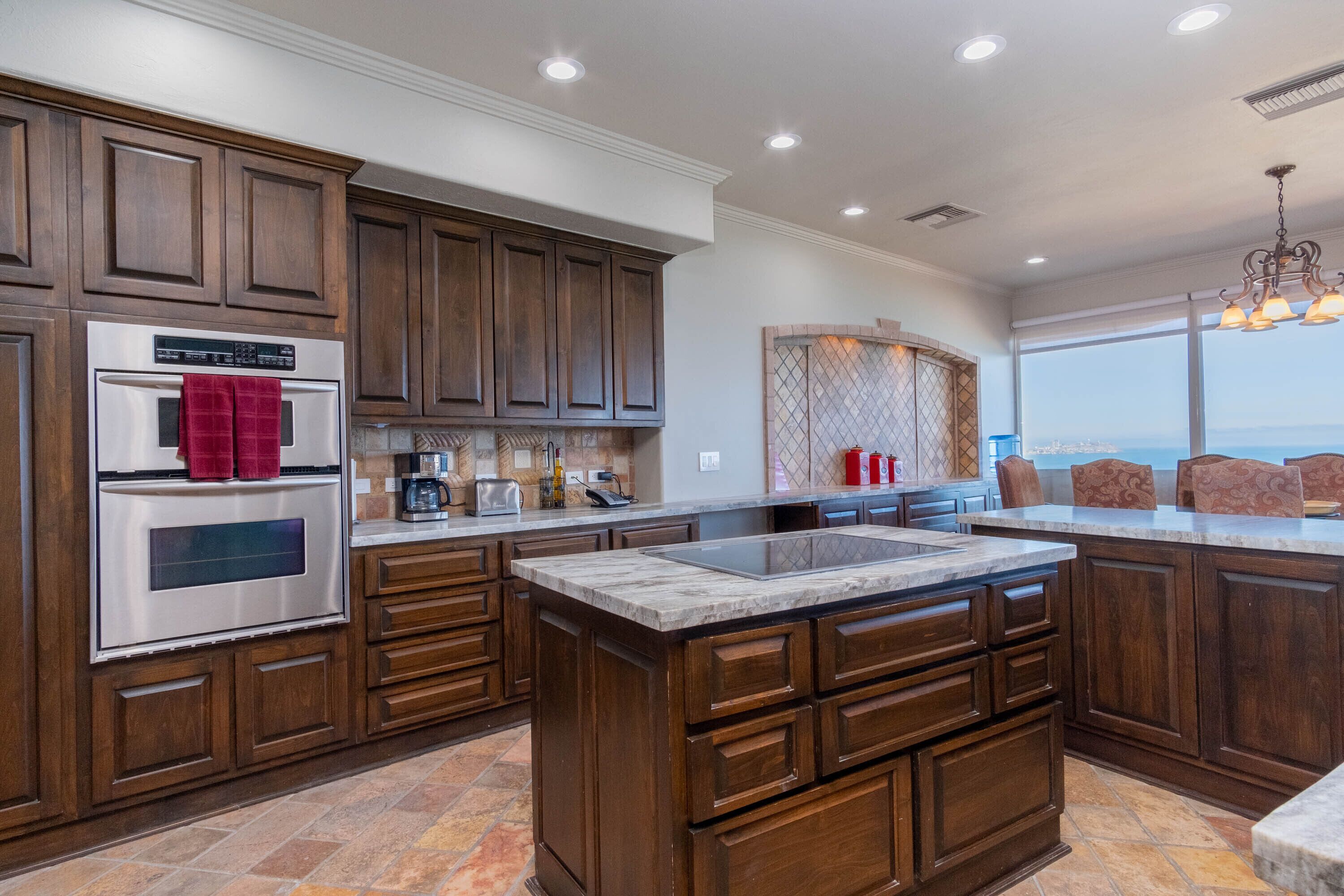 A modern kitchen with dark wood cabinets, a stainless steel oven, and a large island with a sink.
