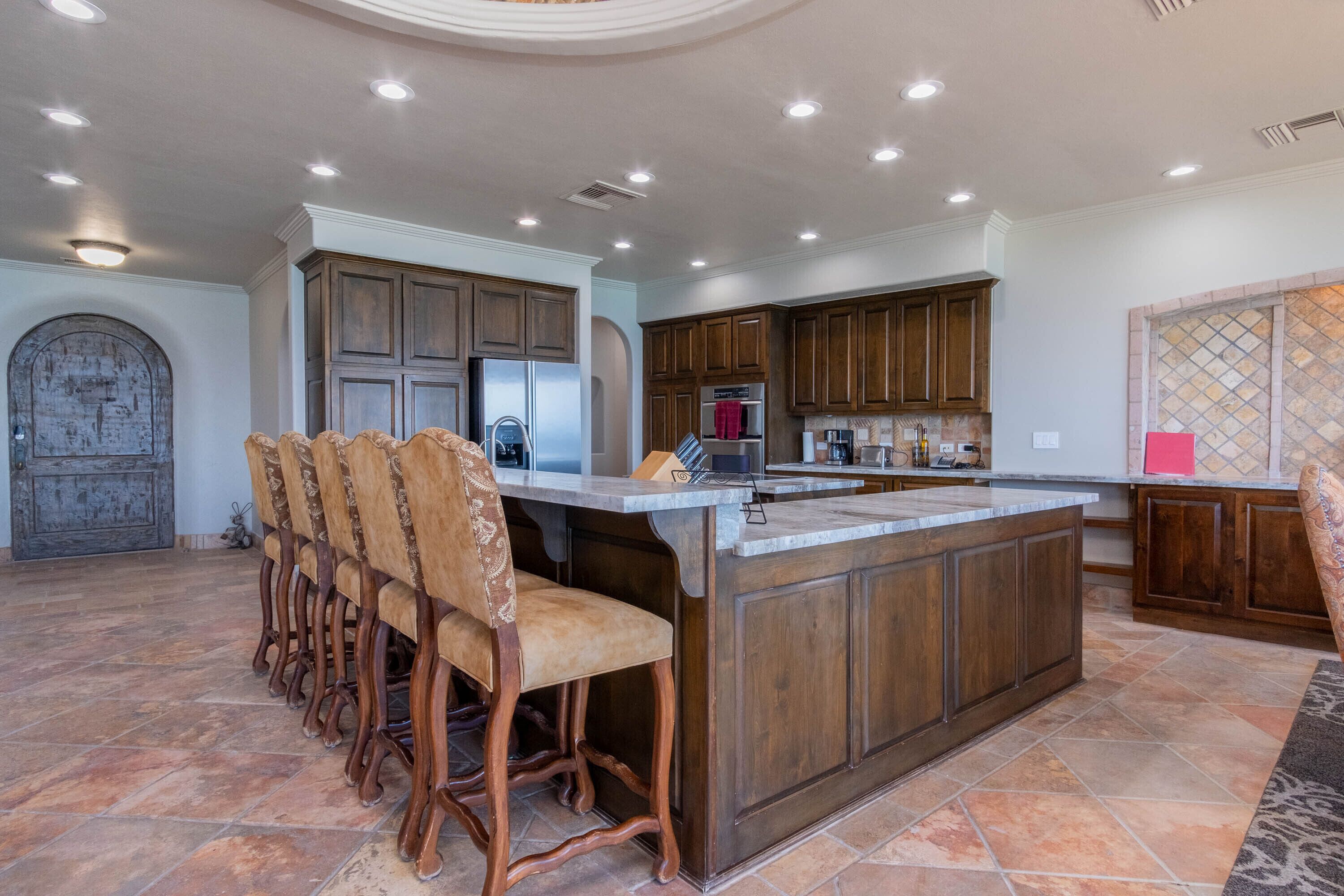 A spacious kitchen with a large island, wooden cabinets, and a stone archway.