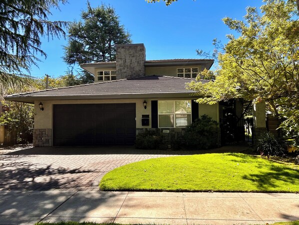 A two-story house with a stone chimney, a garage, and a well-maintained lawn. - Crescent House - Tranquil Downtown Home (Lodi)
