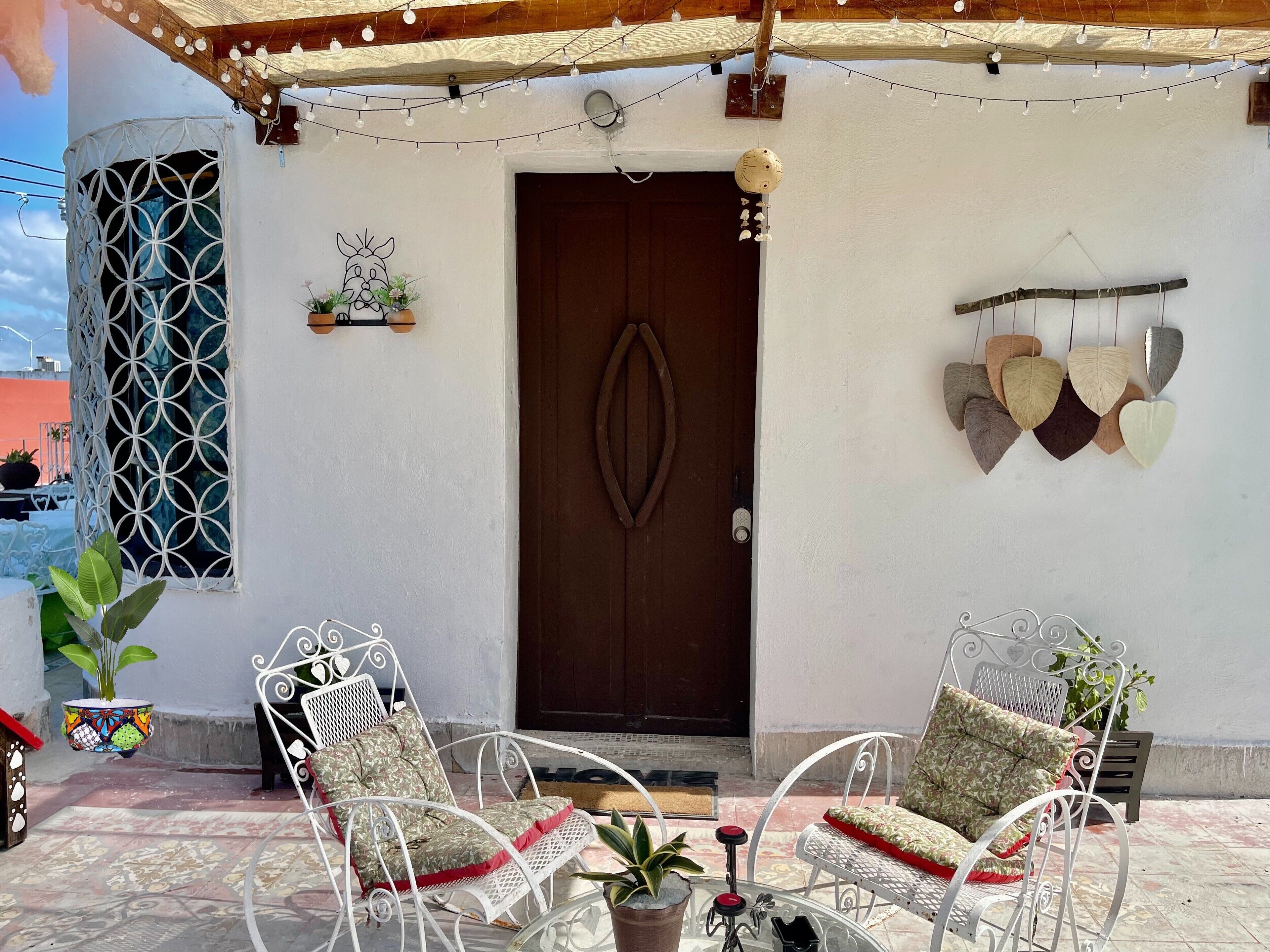 A patio with two white metal chairs, a small table, and a potted plant.