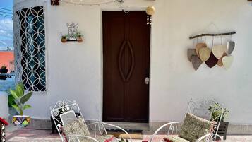 A patio with two white metal chairs, a small table, and a potted plant.