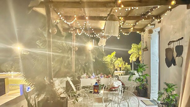 A covered outdoor area with string lights, a bicycle, and potted plants. - La Casa del Colibrí (Campeche)