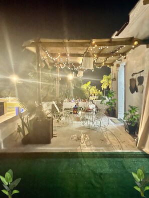 A covered outdoor area with string lights, a bicycle, and potted plants. - La Casa del Colibrí (Campeche)