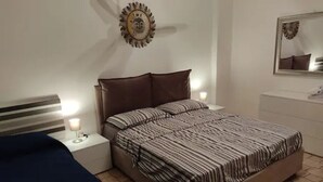 Un dormitorio con una cama, mesitas de noche, una lámpara, un espejo y un adorno en la pared.