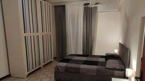 Un dormitorio con cama, armario y mesita de noche con lámpara.
