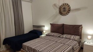 Un dormitorio con una cama, dos mesitas de noche, un adorno en la pared y una cortina.