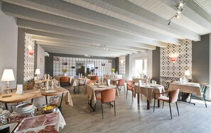 Un amplio comedor con varias mesas y sillas, un techo alto con vigas a la vista y paneles decorativos en las paredes.