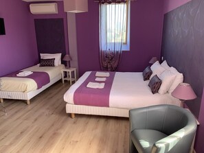 Una habitación con dos camas, una silla y una ventana con cortinas traslúcidas.