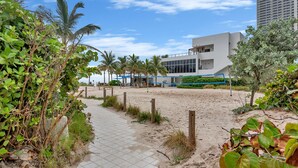 A pathway leading to a modern building with a flat roof and large windows, surrounded by greenery and palm trees. - Hollywood Beach Glam (Hollywood)