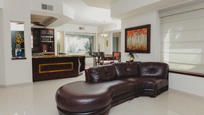Ein modernes Wohnzimmer mit einer ledernen Eckcouch, einem Essbereich mit Tisch und Stühlen sowie einer Küche mit integrierter Kochinsel.