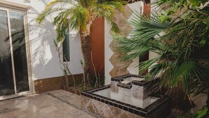 Ein Innenhof mit gefliestem Boden, einer Palme und einem kleinen Wasserspiel.