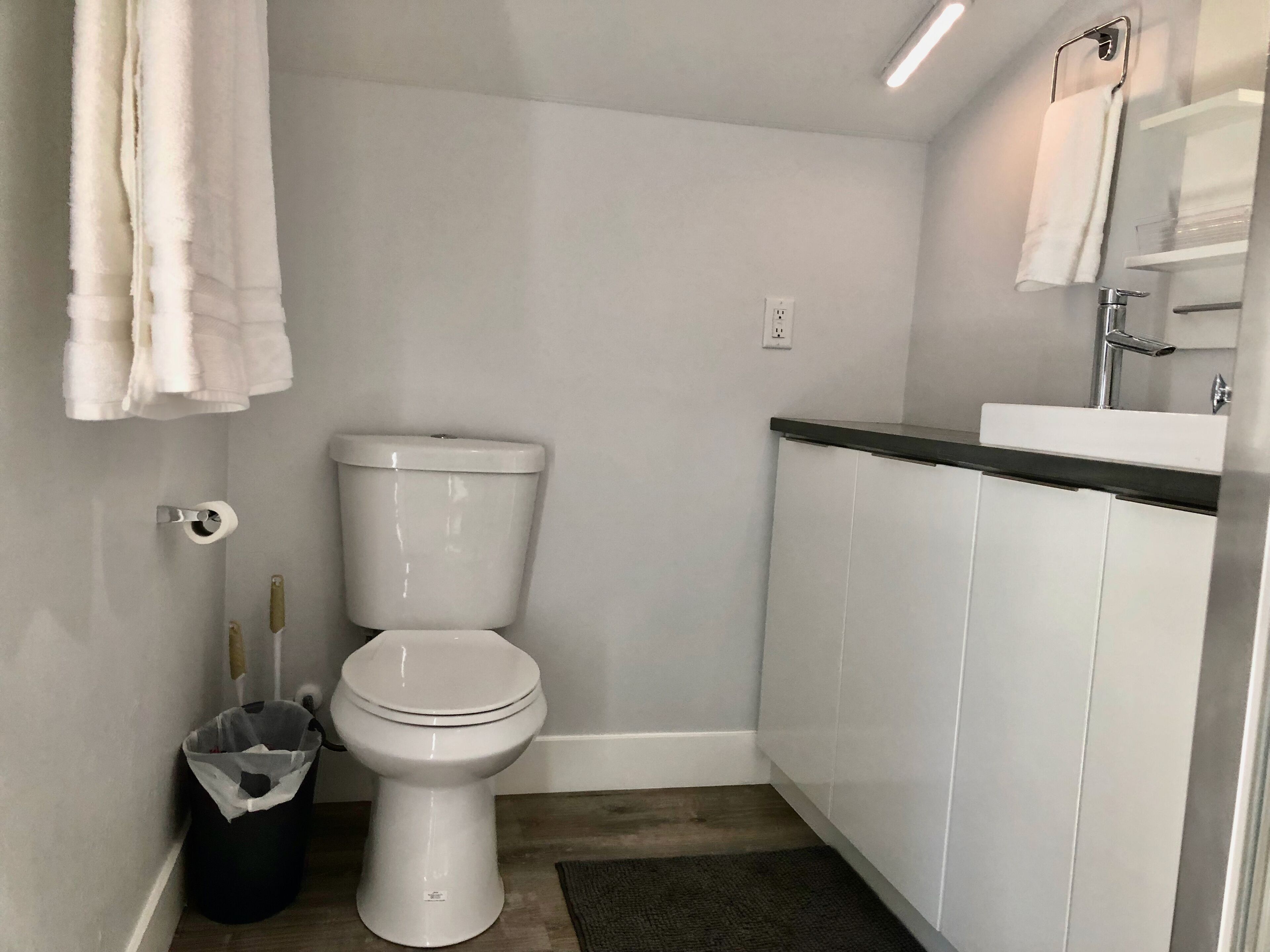 Un baño pequeño y moderno con inodoro, lavabo y perchero para toallas.