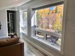 Un pasillo con grandes ventanas que ofrecen vistas del follaje otoñal.