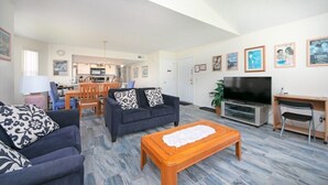 A spacious living area with a dining set, sofas, a TV, and a coffee table. - Spacious 4 Bedroom Condo Retreat! 🏠✨ (Kissimmee)