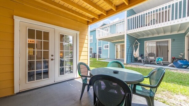 A covered patio with a table and chairs, a sliding glass door, and a balcony with outdoor furniture. - Spacious 4 Bedroom Condo Retreat! 🏠✨ (Kissimmee)